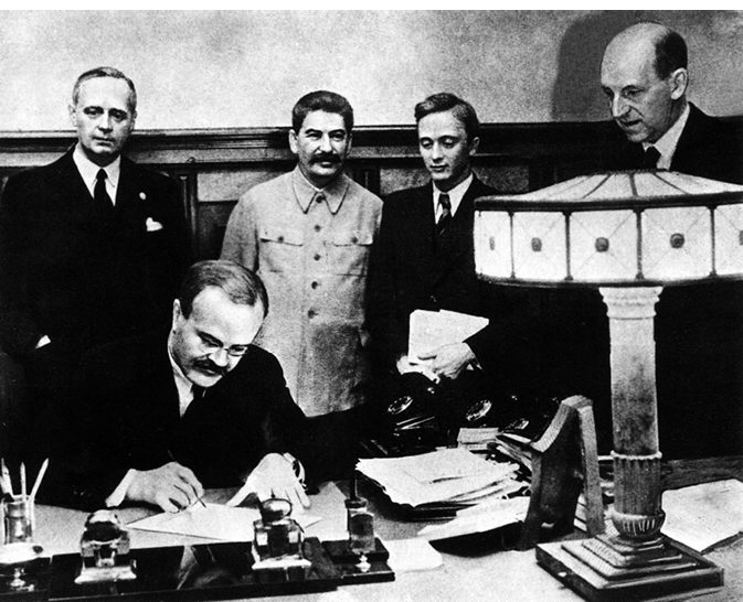Vyacheslav Molotov, Soviet foreign minister, signs the Nazi-Soviet Non-Aggression Treaty in the Kremlin, Moscow on 23 August 1939. Stalin, Nazi foreign minister von Ribbentrop and others look on contentedly